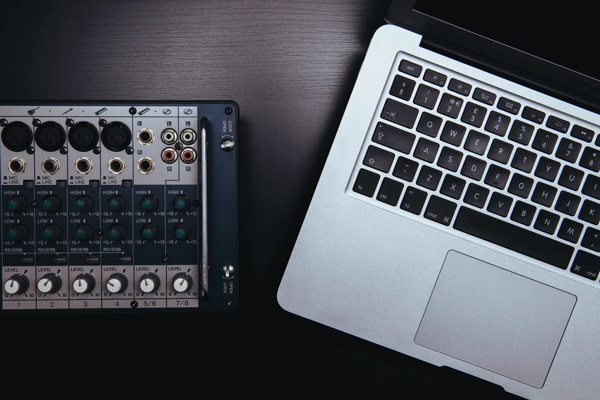 Macbook Pro computer sitting next to an audio mixing board